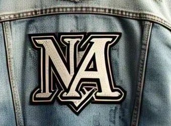 Close-up of a large bordered chenille letter patch stitched to the back of a light wash denim jacket
