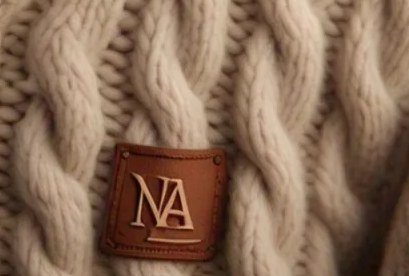 Close-up of a stitched leather patch label on chunky cream cable knit